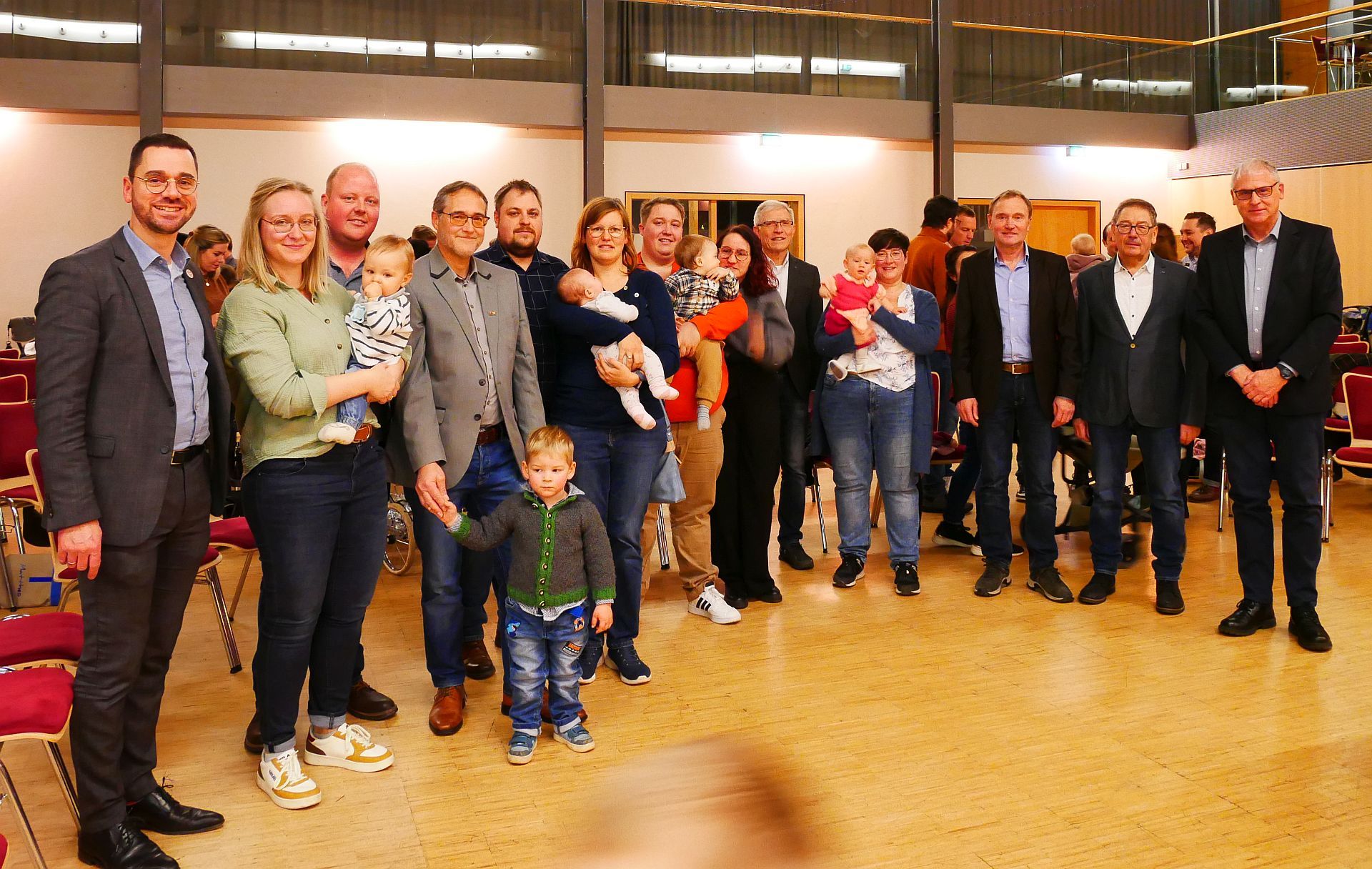 Begrüßung der Neugeborenen in der Gemeinde Großenlüder Bürgermeister Florian Fritzsch (links) mit einigen Eltern mit Kindern sowie den anwesenden Ortsvorstehern aus Großenlüder Jürgen Hübl (5. v. l.), aus Eichenau Norbert Printz (6. v. r.), aus Uffhausen Peter Muth (3. v. r.), aus Bimbach Karl Süss (2. v. r.) und aus Müs Edgar Möller (rechts)