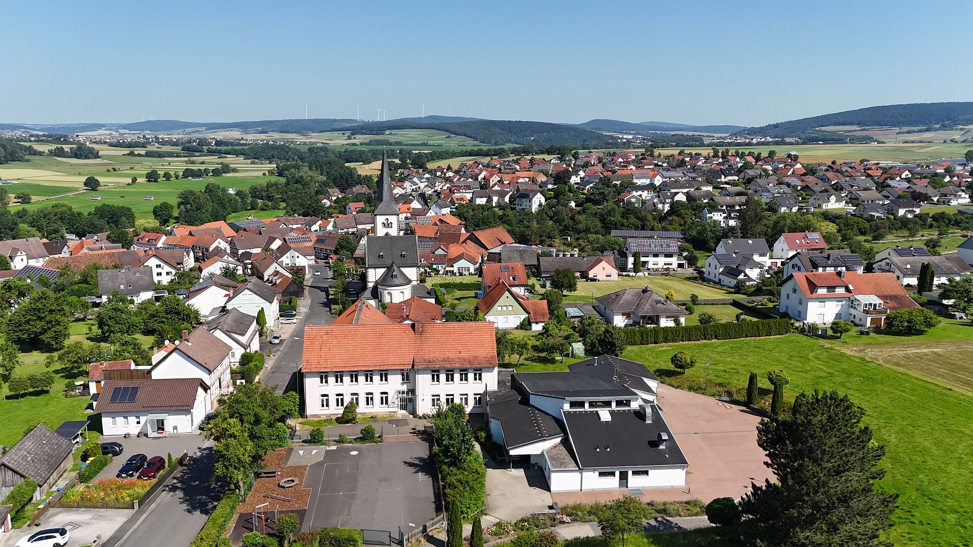 Blick von oben auf Müs mit der Kirche, der Grundschule und dem Bürgerhaus im Mittelpunkt