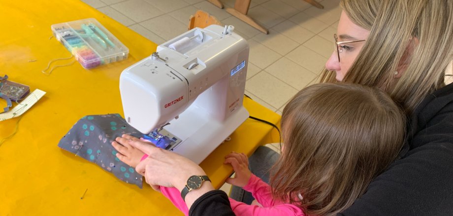 Erzieherin mit Kind an der Nähmaschine