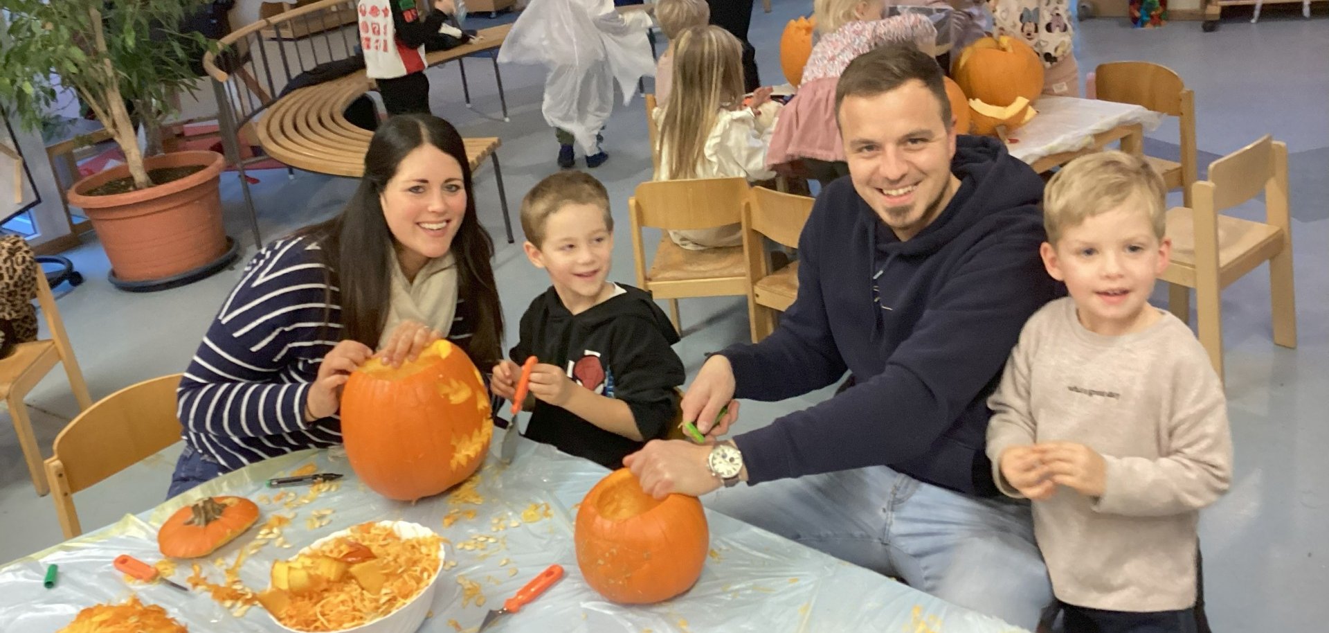 Kinder mit Eltern beim Kürbisschnitzen
