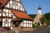 Fachwerkhaus im Ortskern von Lütterz mit Kirche im Hintergrund