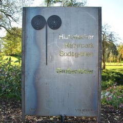 das Metallschild am Eingang mit der der Inschrift Historischer Naturpark Sodegarten Großenlüder - Link öffnet seitenüberlagerndes Dialog-Fenster